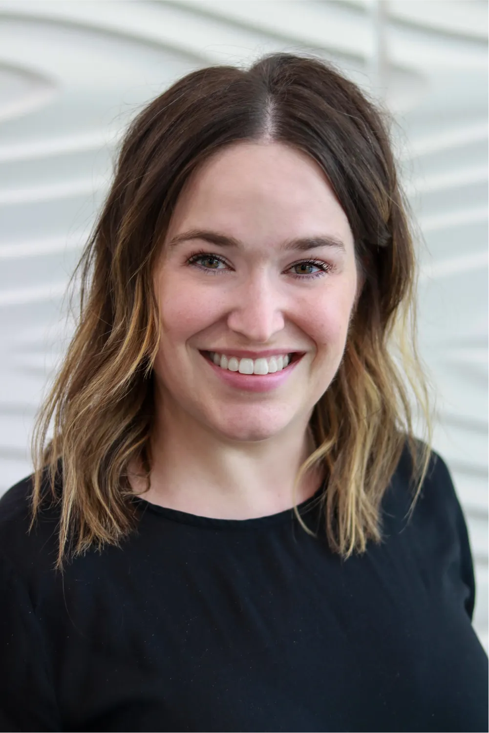 A profile picture of Allison Gordon in front of a white wall with a raised wave pattern.