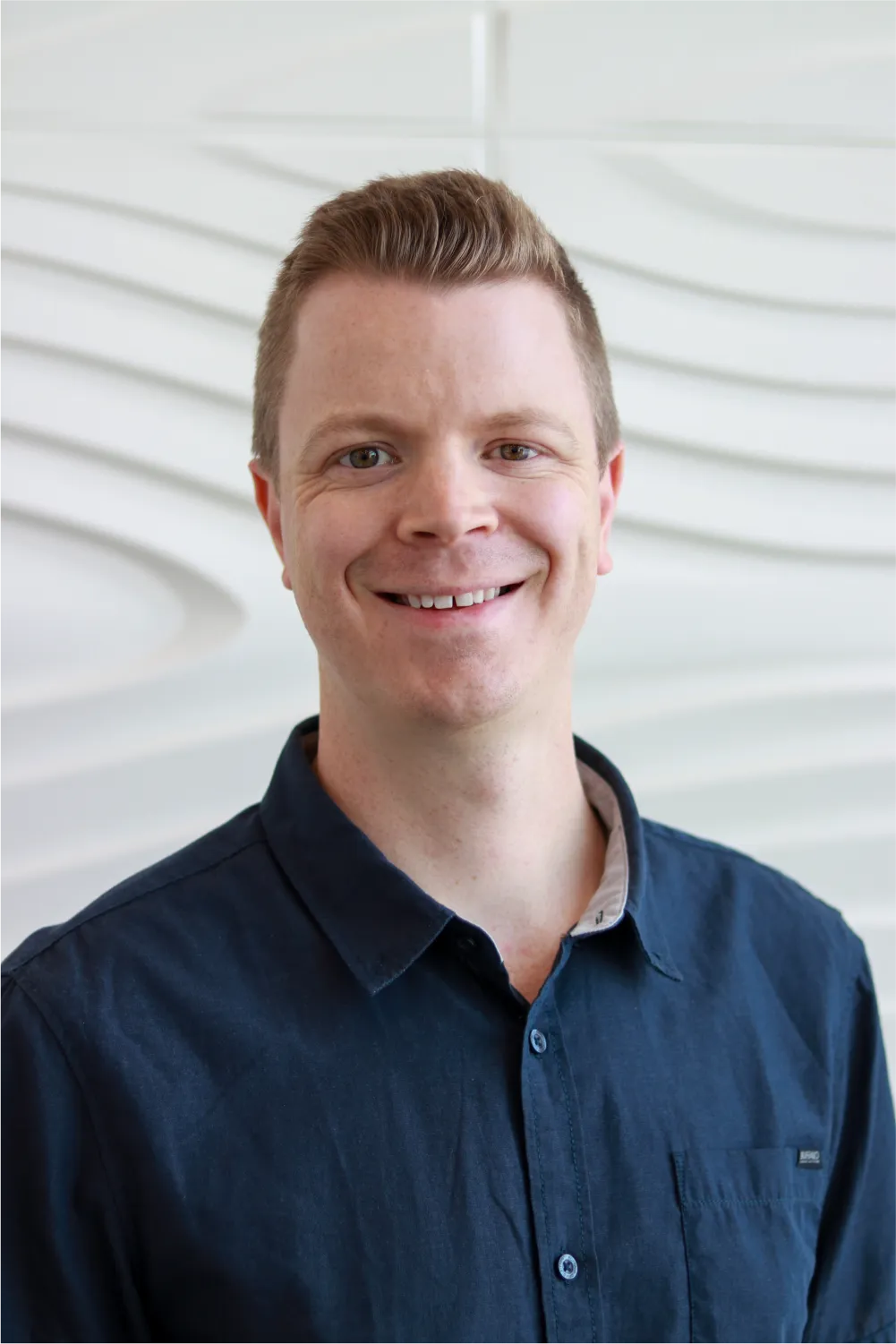 A profile picture of Matt Epp in front of a white wall with a raised wave pattern.