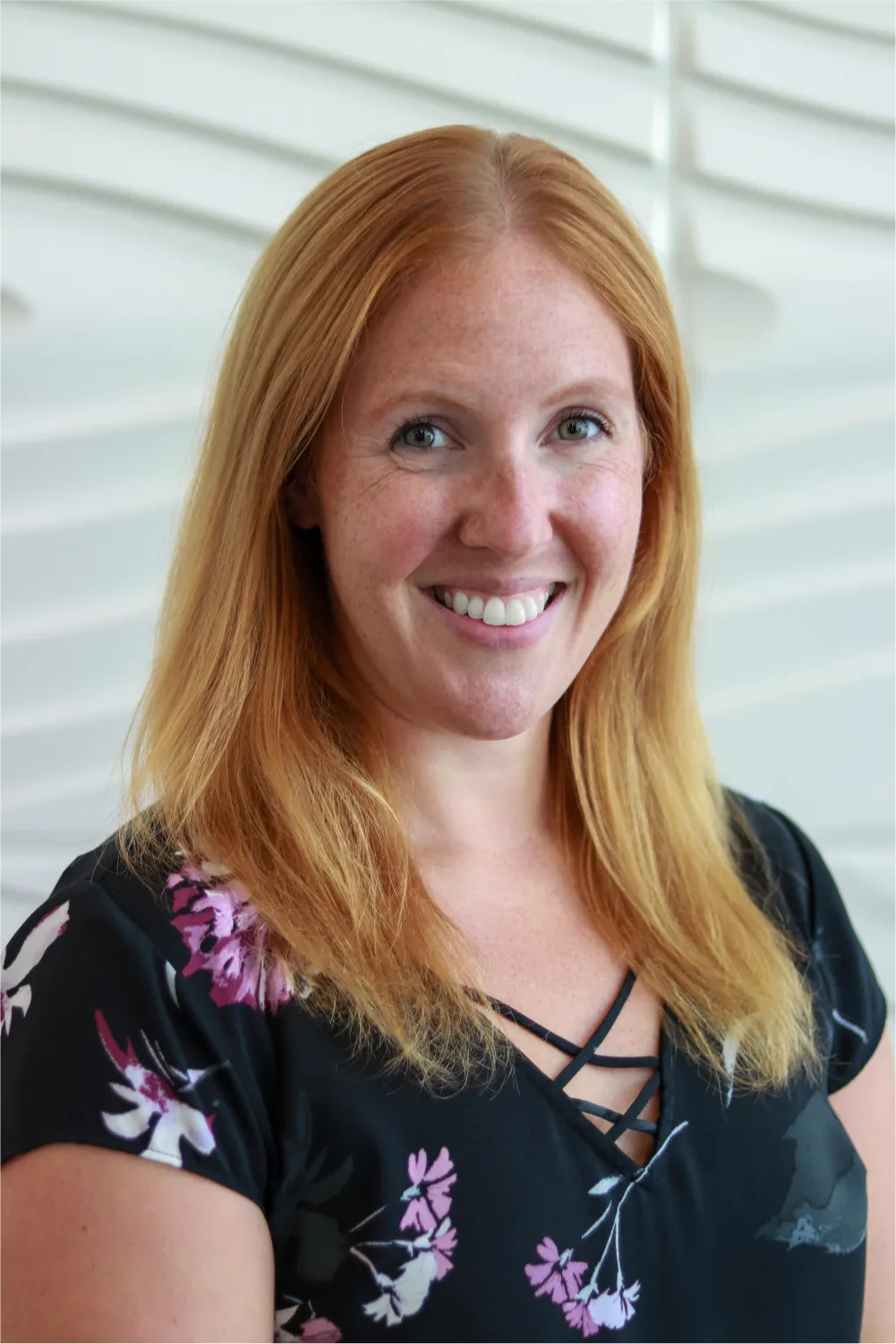 A profile picture of Stephanie Hnatiuk in front of a white wall with a raised wave pattern.