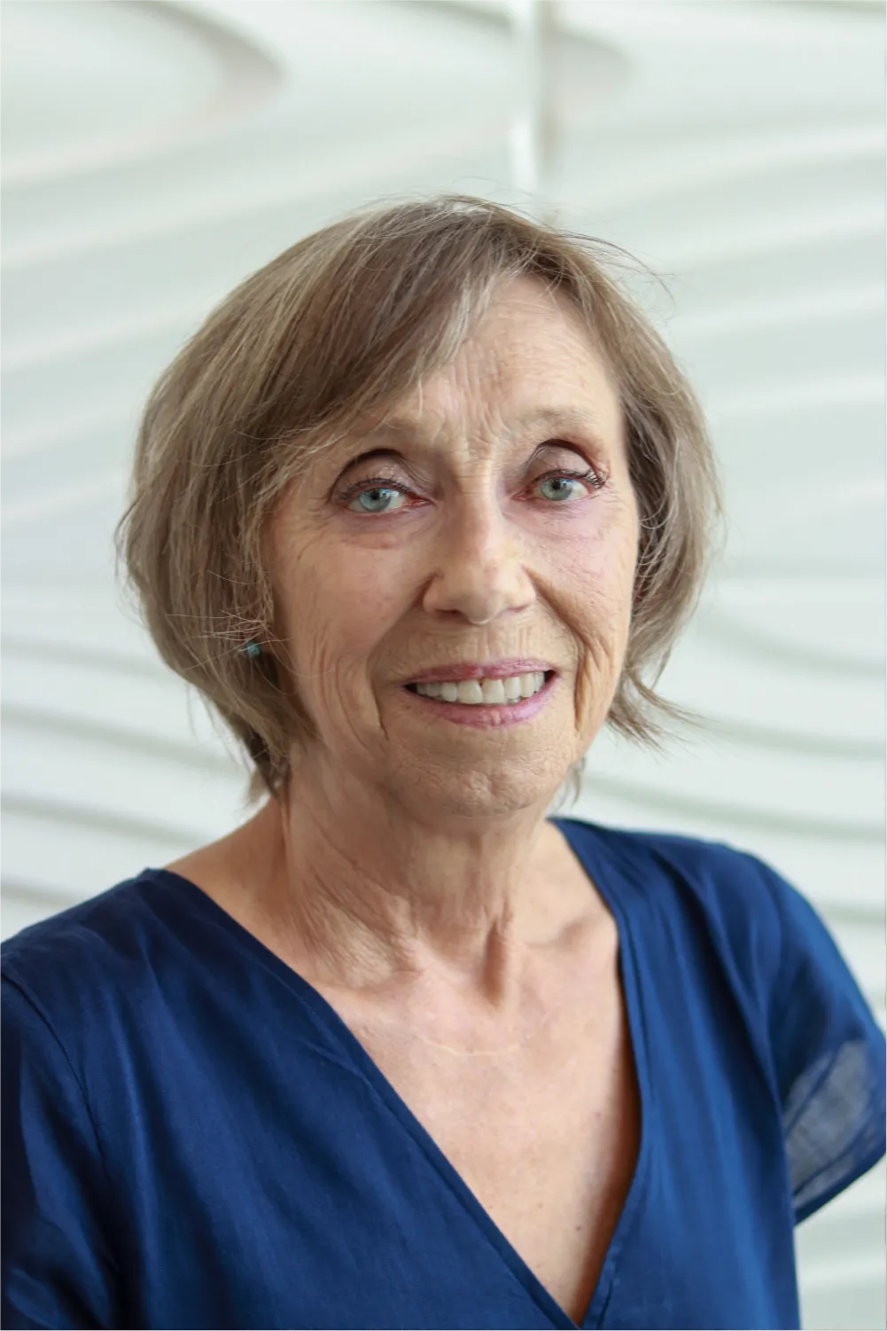 A profile picture of Judy Crawford in front of a white wall with a raised wave pattern.