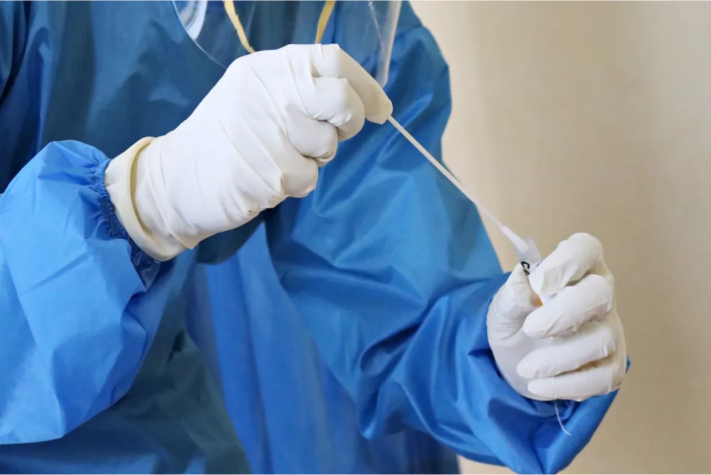 A photo of a lab technician using a medical swab and a test tube.
