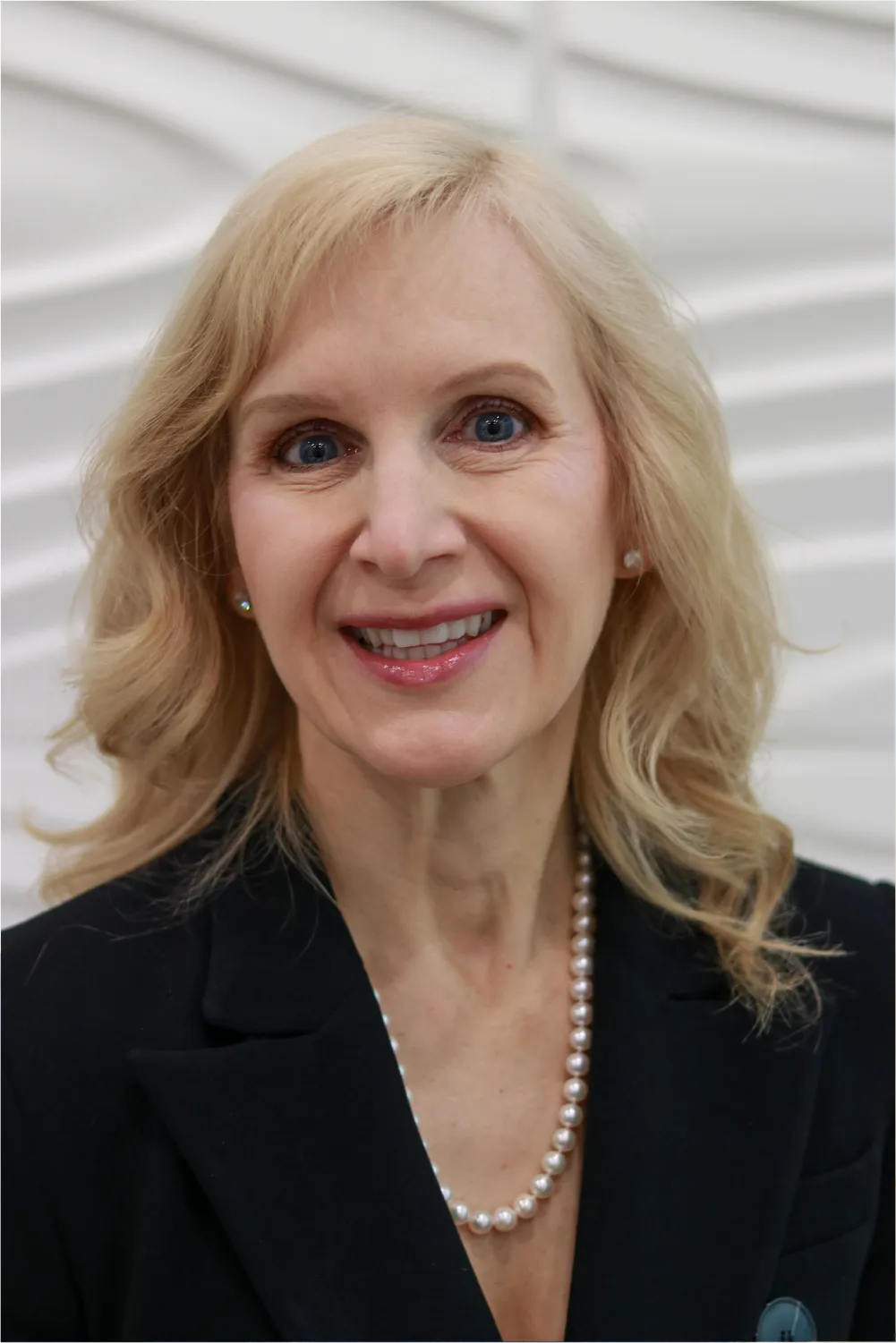 A profile picture of Dr. Karen Braun in front of a white wall with a raised wave pattern.